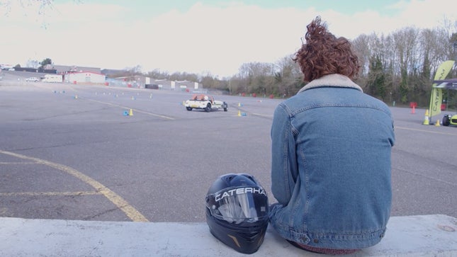 The photo shows a person sitting on a wall with a helmet next to him. 